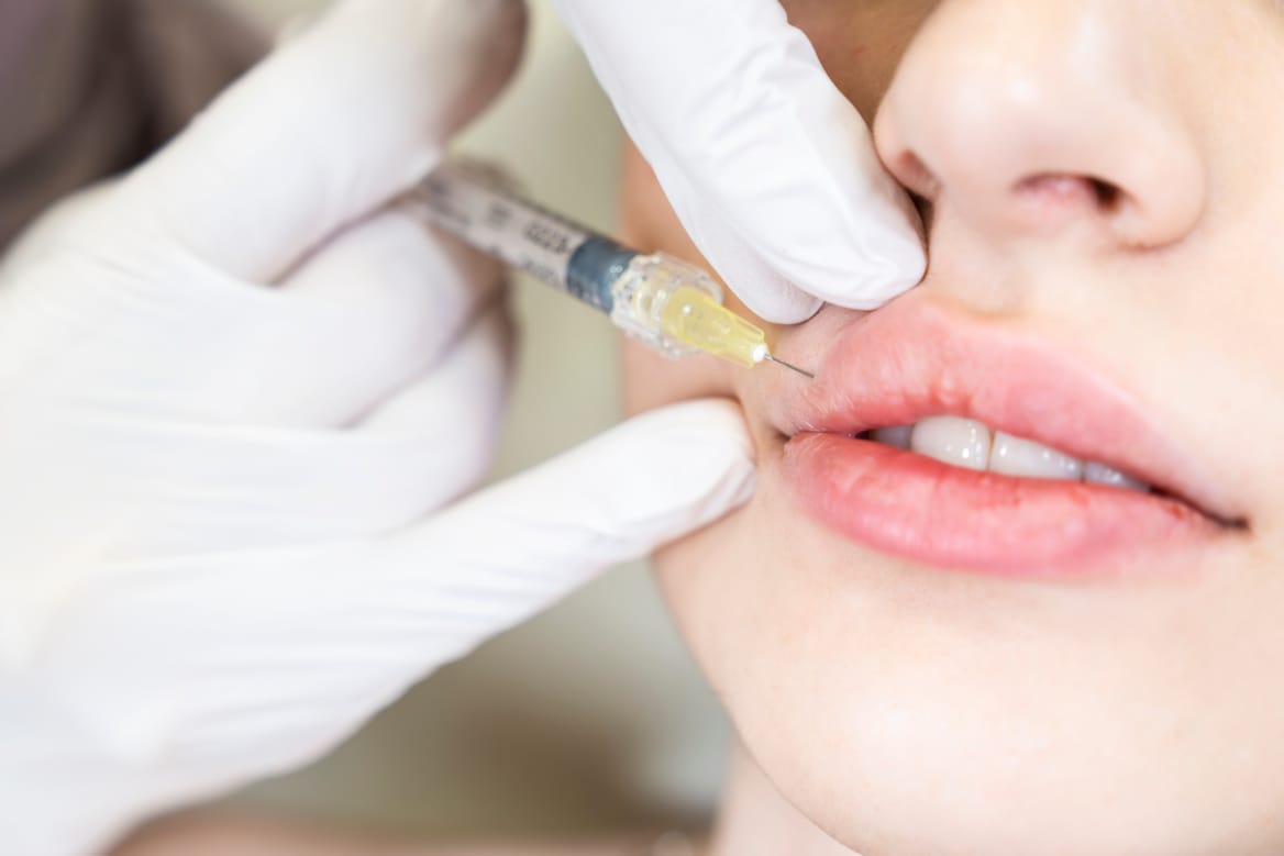 young woman gets injection of botox in her lips. woman in beauty
