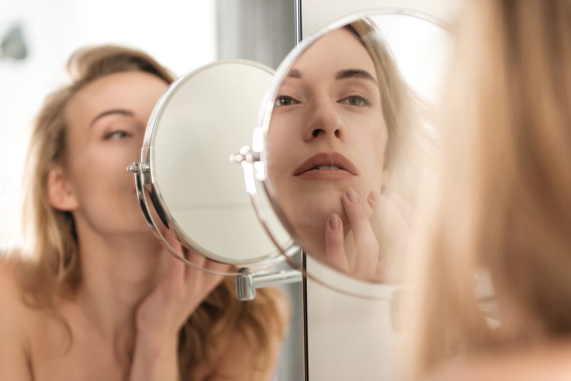 gorgeous young naked woman looking at mirror.
