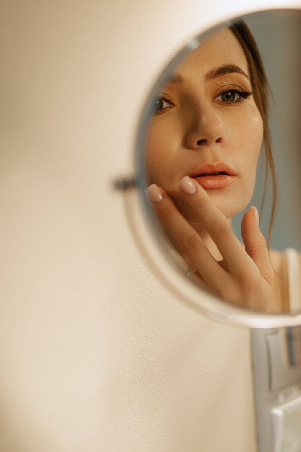 Gezicht in spiegel, huidverbetering en huidverzorging bij Glow Clinic in Nederland.